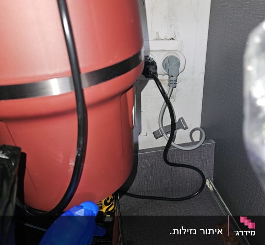 מיכל אדום עם כבל חשמל ושקע בקיר